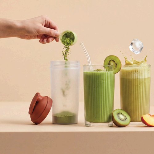 Kiwi dropped into two green matcha protein shakes